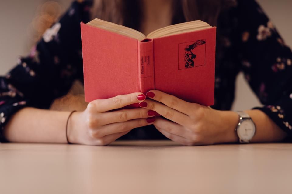 Pessoa lendo um livro de capa vermelha