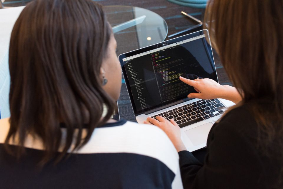 Duas pessoas analisando código-fonte na tela de um notebook